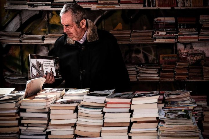 mężczyzna przegląda książkę na stoisku księgarskim