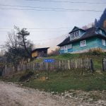 drewniany dom otoczony płotem na ukraińskiej wsi