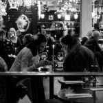 dwie kobiety siedzące przy stoliku w restauracji, pijące wino