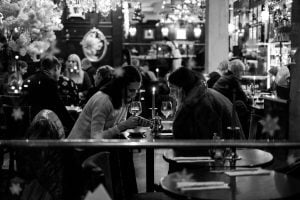 dwie kobiety siedzące przy stoliku w restauracji, pijące wino