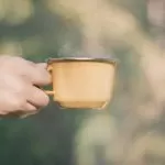 dłoń trzymają kubek kawy