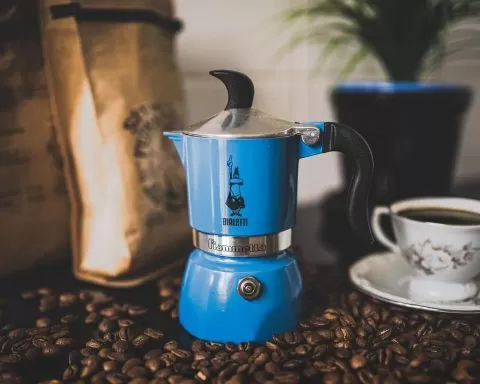 kawiarka moka stojąca na stole pośród ziaren kawy