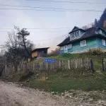 drewniany dom otoczony płotem na ukraińskiej wsi