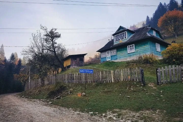 drewniany dom otoczony płotem na ukraińskiej wsi