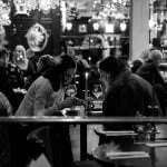 dwie kobiety siedzące przy stoliku w restauracji, pijące wino