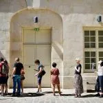 ludzie stojący w kolejce przed budynkiem