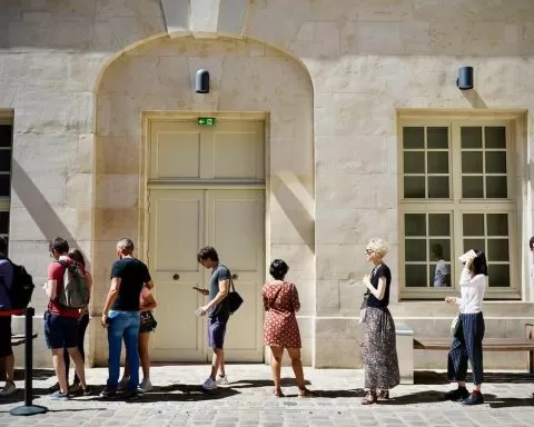 ludzie stojący w kolejce przed budynkiem